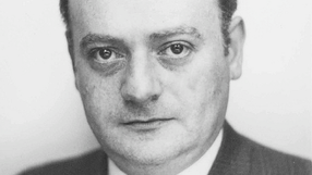 Czarnoskalowe zdjęcie portretowe mężczyzny w garniturze.