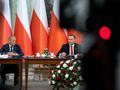 Donald Tusk, Karol Nawrocki przy stole, za nimi polskie flagi. U dołu bukiet z czerwonych i białych róż.