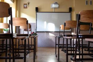 Pusta klasa szkolna z drewnianymi krzesłami, tablicą i rzutnikiem