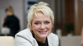 Małgorzata Ostrowska z krótkimi blond włosami, uśmiechająca się w jasnym otoczeniu.