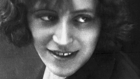 Portret młodej kobiety o kręconych włosach, z uśmiechem i wyrazistym spojrzeniem.