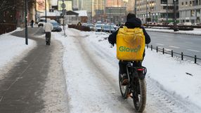 Kurier Glovo mknie po chodniku