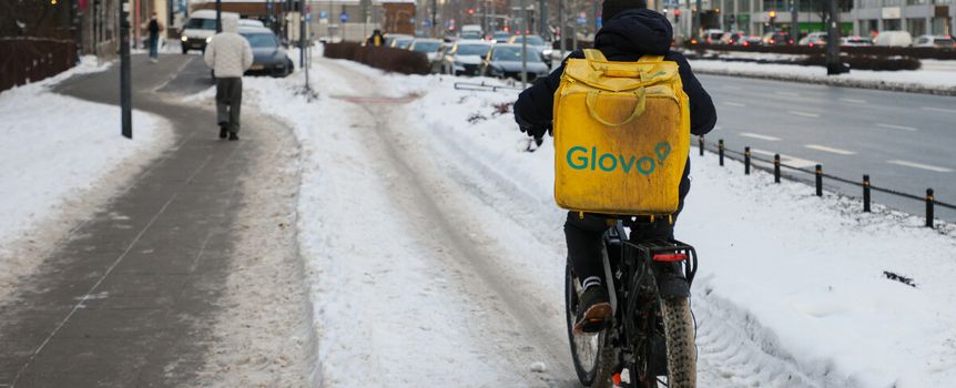Kurier Glovo mknie po chodniku