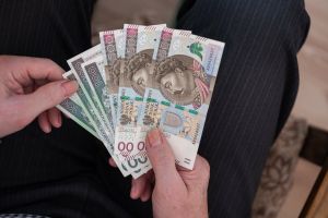 Osoba trzyma kilka polskich banknotów o różnych nominałach w dłoni.