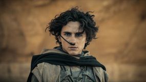 Na zdjęciu filmowy Paul Atryda z kręconymi włosami i niebieskimi oczami, ubrany w szare szaty.