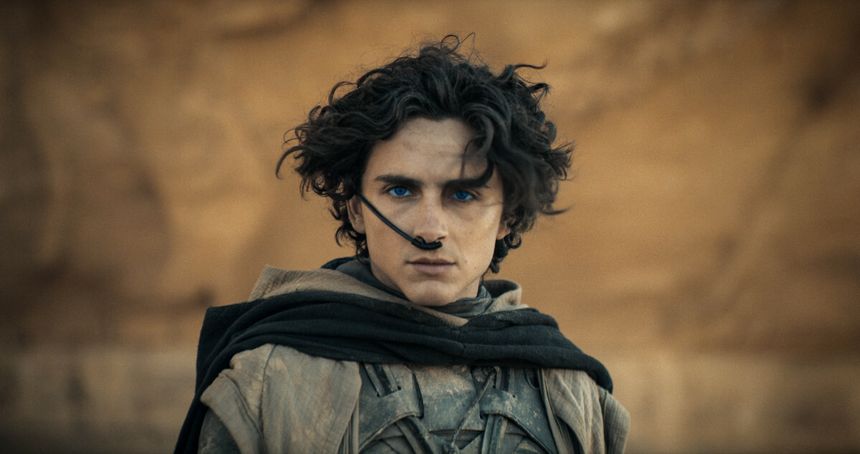 Na zdjęciu filmowy Paul Atryda z kręconymi włosami i niebieskimi oczami, ubrany w szare szaty.