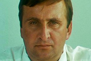 Zdjęcie mężczyzny o krótkich, ciemnych włosach, patrzącego w kamerę, z neutralnym wyrazem twarzy.