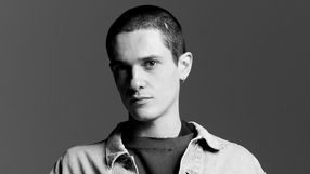 Mężczyzna z krótkimi, jasnymi włosami, w odzieży w stylu casual, patrzy w obiektyw.