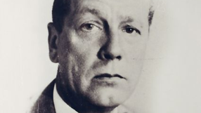 Mężczyzna w garniturze, z poważnym wyrazem twarzy, czarno-białe zdjęcie portretowe.