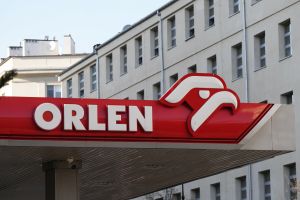 Znak stacji paliw ORLEN na tle budynków w jasny dzień.