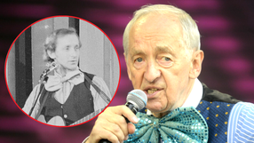 Andrzej Rosiewicz z mikrofonem, w kolorowym ubraniu, na scenie. W tle zdjęcie sprzed lat.