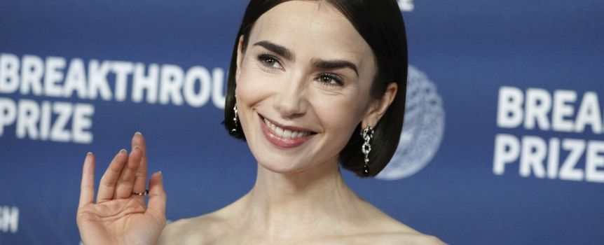 Na zdjęciu uśmiechająca się kobieta z krótkimi warkoczami, w eleganckiej sukni, na niebieskim tle.