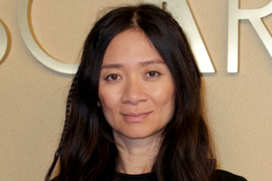 Na zdjęciu portret Chloé Zhao z długimi, ciemnymi włosami, uśmiechającej się lekko.