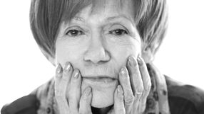 Na zdjęciu widoczna jest Maria Czubaszek, z rękoma na twarzy, w stonowanej tonacji.