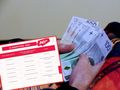 Na zdjęciu widać dłoń trzymającą banknoty oraz tabelę z informacjami o emeryturze.
