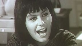 Kobieta z krótkimi, ciemnymi włosami, uśmiecha się i śpiewa. Czarnobiałe, retro zdjęcie.