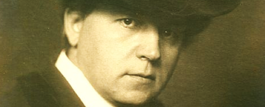 Zdjęcie mężczyzny w kapeluszu, patrzącego intensywnie w obiektyw. Czarno-biała, stara fotografia.