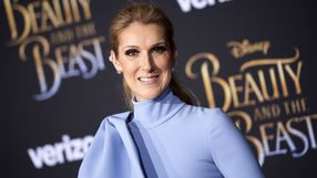 Kobieta w błękitnej sukience uśmiecha się na tle plakatu filmu 