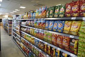 Aksamitne półki sklepu pełne kolorowych paczek chipsów różnych smaków.