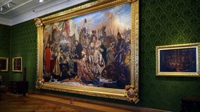 Obraz przedstawiający historyczne postacie w bogato zdobionej ramie na zielonej ścianie.
