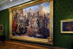 Obraz przedstawiający historyczne postacie w bogato zdobionej ramie na zielonej ścianie.