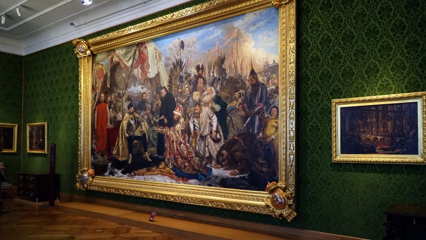 Obraz przedstawiający historyczne postacie w bogato zdobionej ramie na zielonej ścianie.
