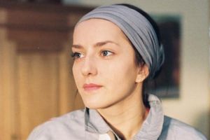 Portret młodej kobiety z chustką na głowie, patrzącej w dal w naturalnym świetle.