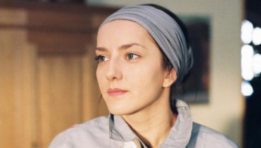 Portret młodej kobiety z chustką na głowie, patrzącej w dal w naturalnym świetle.
