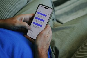 Mężczyzna w granatowej koszulce trzyma telefon, na którym otwarta jest aplikacja do terapii.