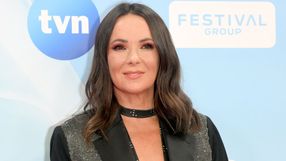 Kobieta o długich, ciemnych włosach, uśmiechająca się na tle niebieskiego tła z logo TVN.