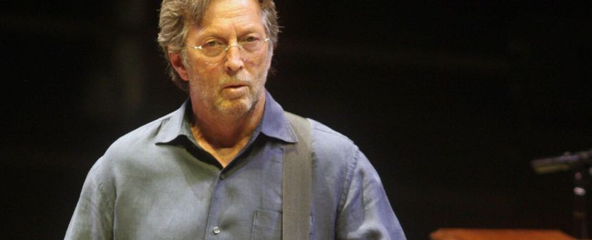 Na zdjęciu mężczyzna z gitarą, w okularach, w niebieskiej koszuli, na scenie.
