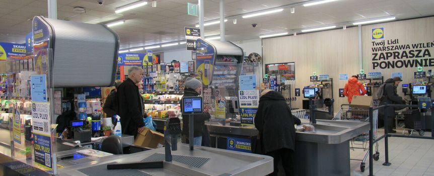 Sklep Lidl, kasy samoobsługowe, klienci przy kasach, produkty spożywcze na półkach.