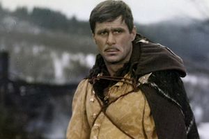 Mężczyzna w średniowiecznym stroju, z zamyśloną miną, w tle rozmyta zima i krajobraz.