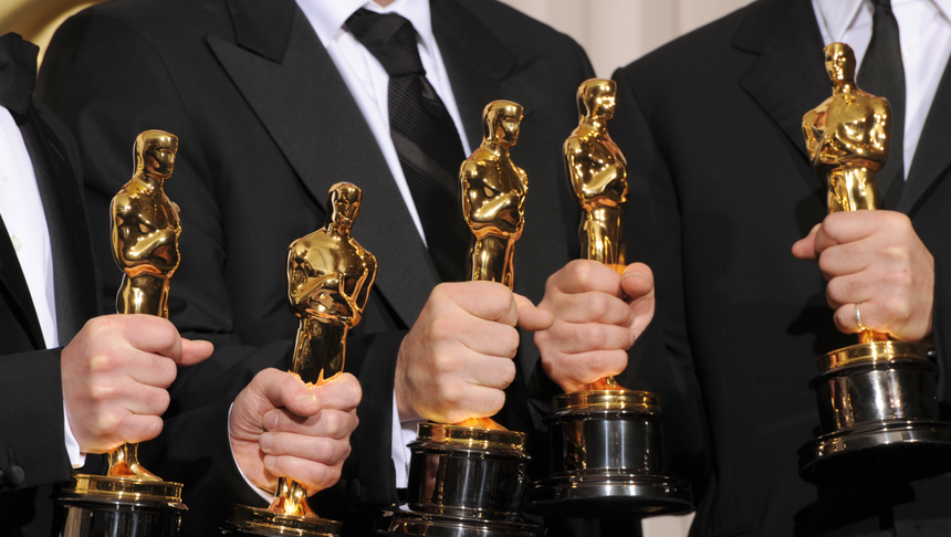 Grupa osób w eleganckich strojach trzyma złote statuetki Oscarów.