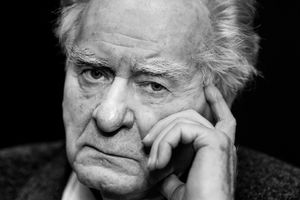Wiesław Myśliwski. Mężczyzna z siwymi włosami, zamyślony, patrzy prosto w obiektyw, opierając rękę na twarzy.