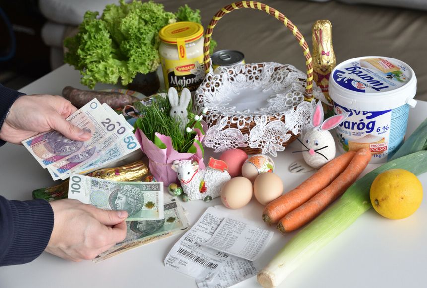 Na stole leżą zakupy wielkanocne: jedzenie, dekoracje oraz pieniądze w rękach.