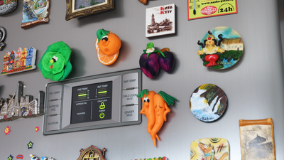 Zestaw kolorowych magnesów na metalowej lodówce, w tym warzywa i miasta.