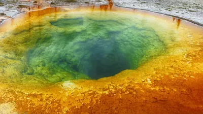 Jasnoniebieska, okrągła dziura w ziemi otoczona kolorowymi minerałami i osadami.