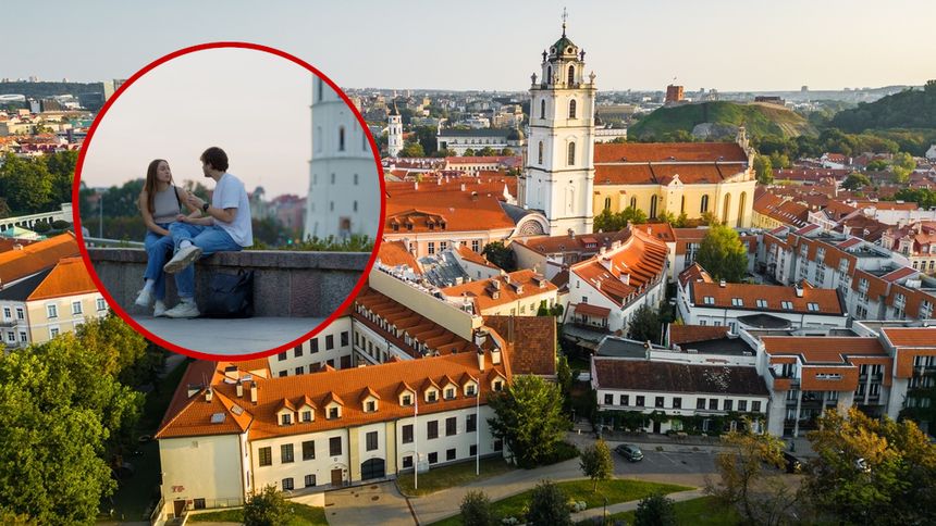 Widok na miasto z parą siedzącą na murku, w tle kościół i dachy budynków.
