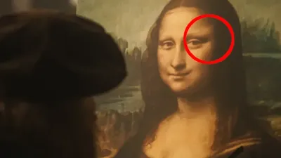 Na zdjęciu mężczyzna w kapeluszu obserwuje obraz Mona Lisy z wyróżnionym owalem na twarzy.