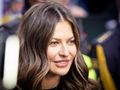 Na zdjęciu uśmiechająca się Anna Lewandowska z długimi, falowanymi włosami. W tle widoczni ludzie.