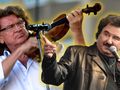 Na zdjęciu dw&oacute;ch muzyk&oacute;w: jeden gra na skrzypcach, drugi śpiewa do mikrofonu.