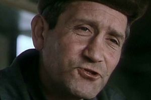 Mężczyzna w ciemnym ubraniu z wyraźnym uśmiechem.