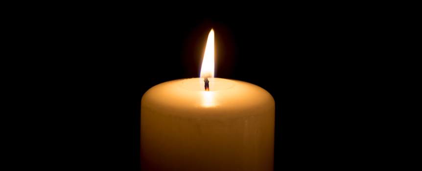 Świeca stołowa z płomieniem na czarnym tle, symbolizująca spokój i refleksję.