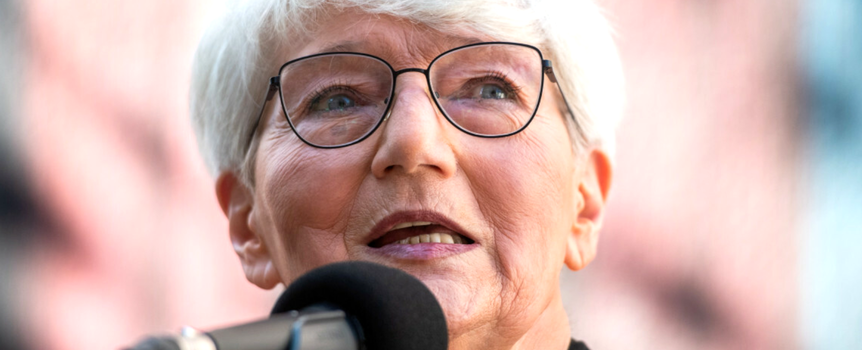 Małgorzata Musierowicz mówi do mikrofonu. Tło jest rozmyte.