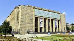 Muzeum Narodowe w Krakowie z ogrodem na pierwszym planie. Jasne niebo w tle.