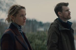 Dwójka ludzi stoi na zewnątrz, w tle widoczna mglista sceneria. Mężczyzna i kobieta są zamyśleni.