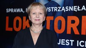 Na zdjęciu uśmiechnięta kobieta w ciemnej sukience, w tle widoczny duży napis: 