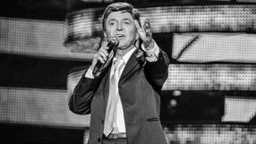 Na zdjęciu Jerzy Połomski. Mężczyzna w garniturze śpiewa do mikrofonu na scenie, z gestem wyrażającym emocje.