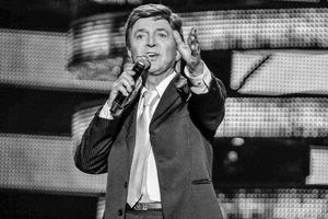 Na zdjęciu Jerzy Połomski. Mężczyzna w garniturze śpiewa do mikrofonu na scenie, z gestem wyrażającym emocje.